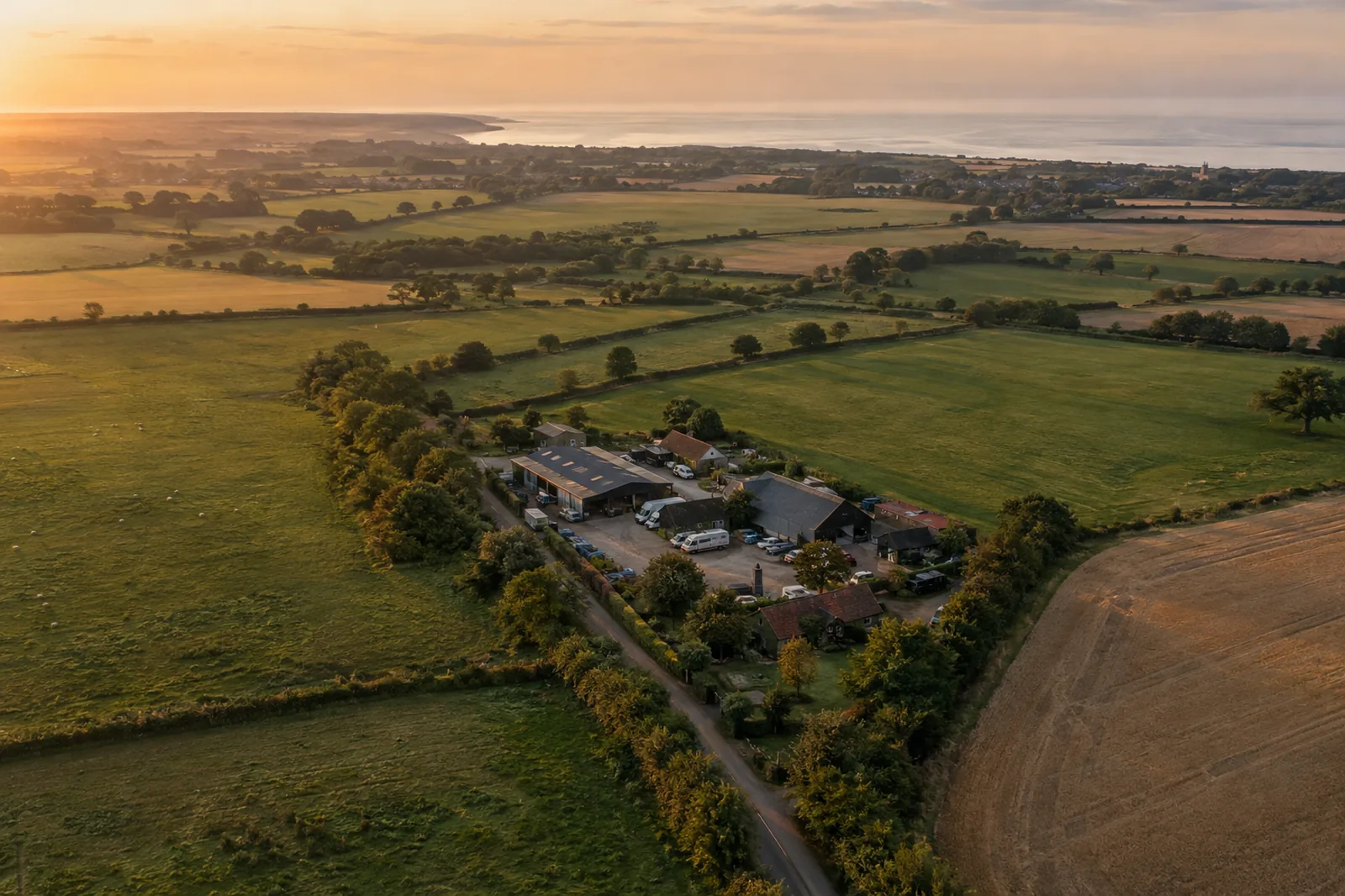 Aerial drone view of a Suffolk business yard surrounded by farmland at golden hour